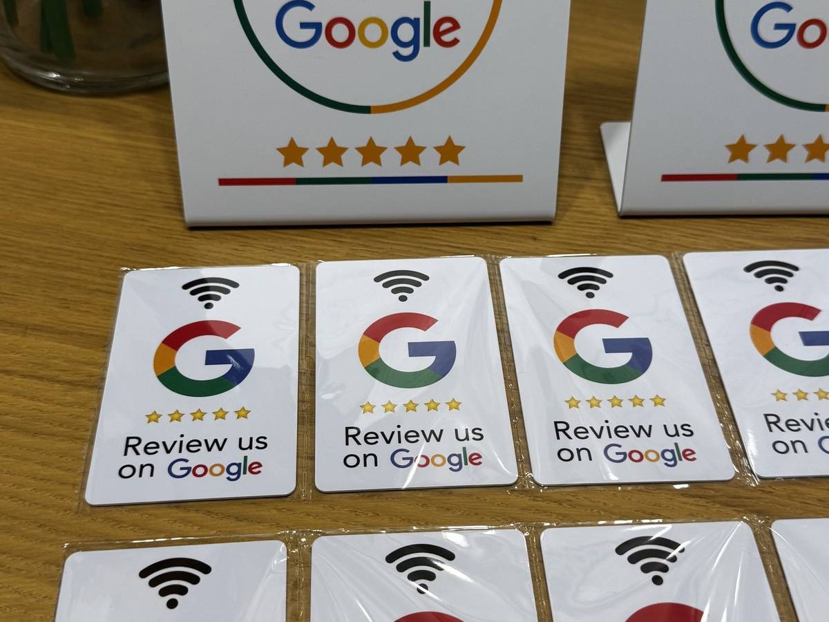 Két NFC-s Google-értékelő tábla és tíz értékelőkártya fa asztalon